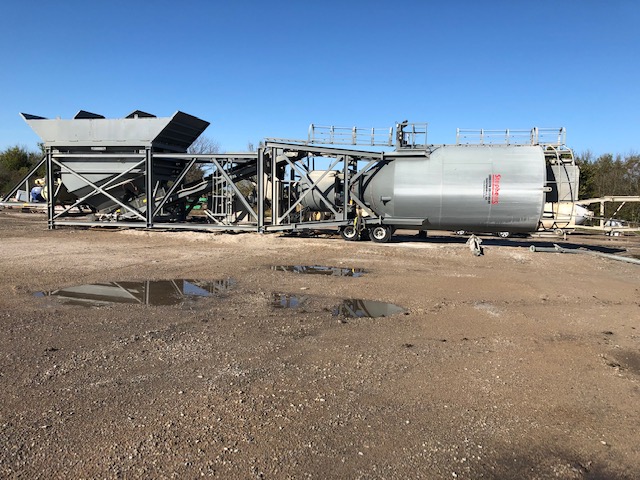 Dirt, metal structure, round tank, blue sky