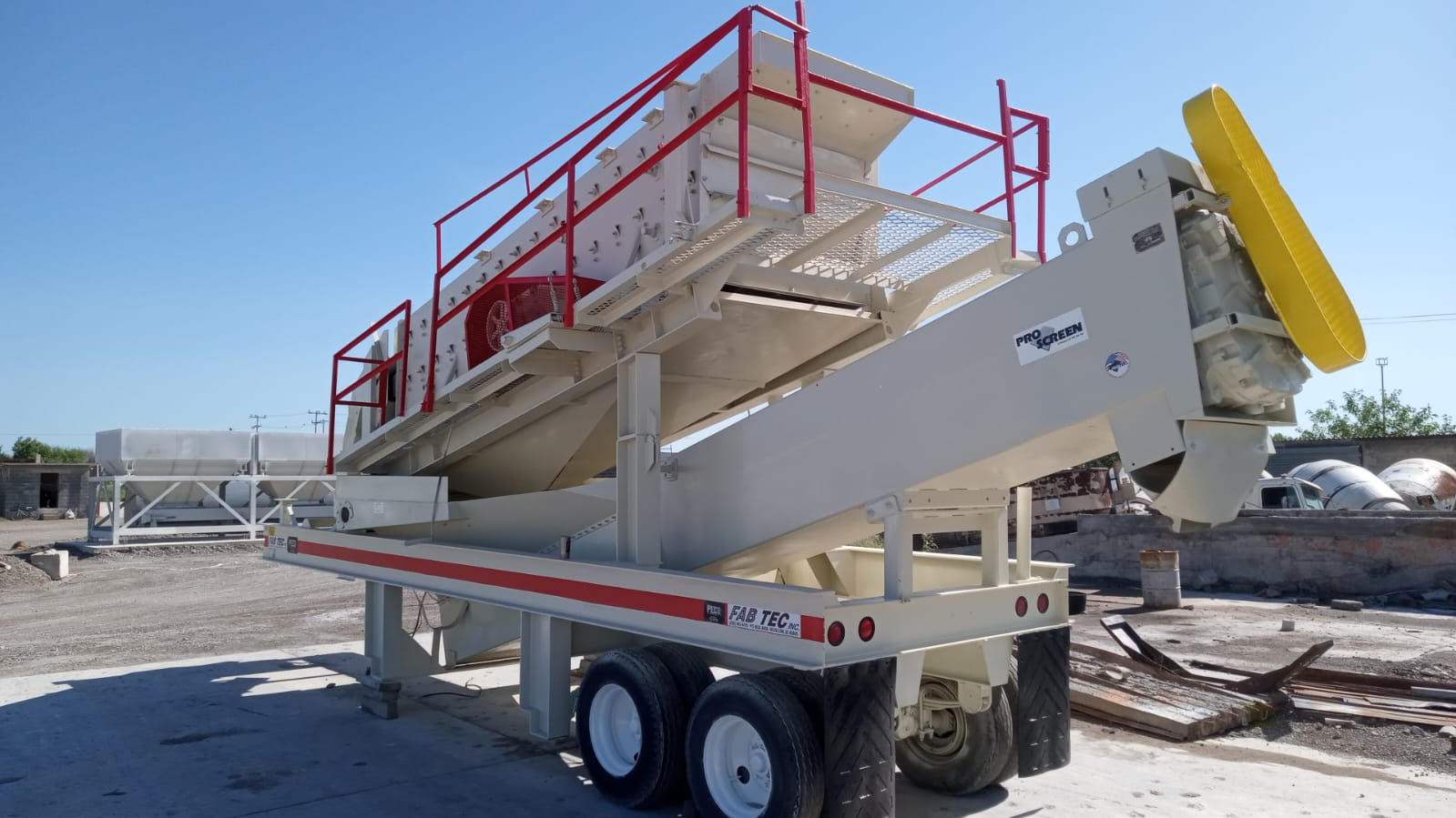 blue sky, tan equipment, shadows on gravel